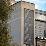 a large black banner hanging on a tall brick building displaying a list civil disobedience forms
