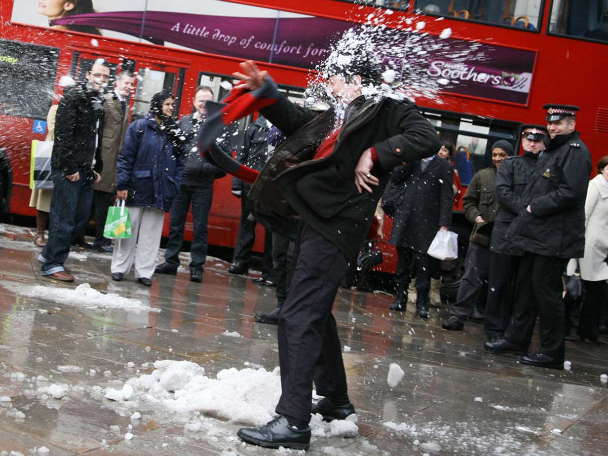 a man in a suit being hit in the face with a snowball