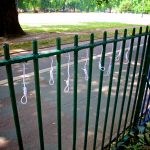 8 small string nooses hang from in between green park railings