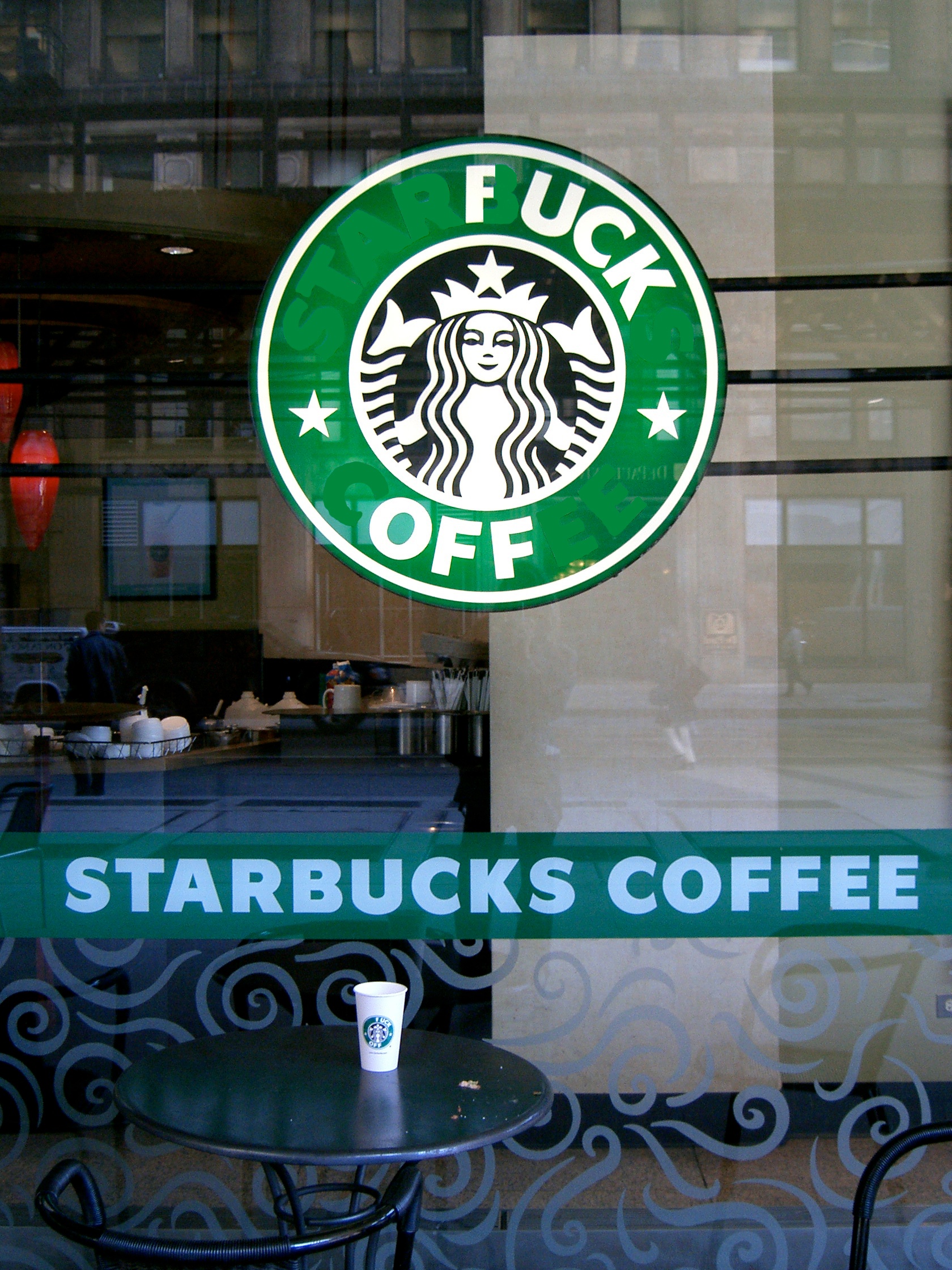 the front glass window of a Starbucks coffee shop with adapted logo to read 'fuck off'