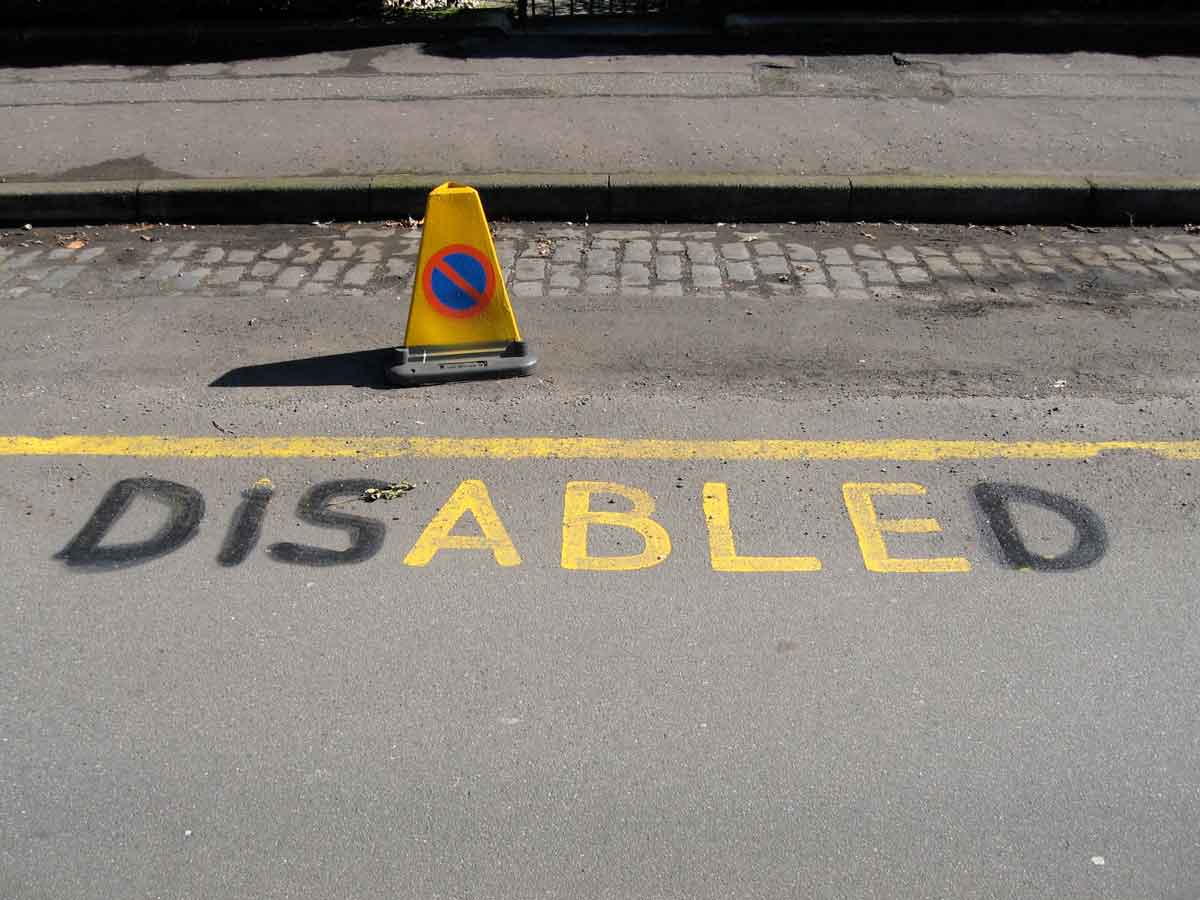yellow disabled parking sign with the letters D I S D blacked out so that ABLE reads in yellow