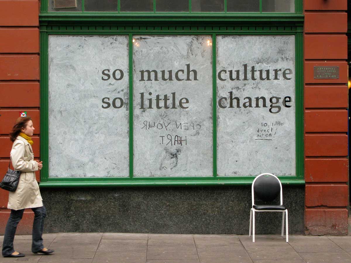 whitewashed shop window with the words 'so much culture so little change' exposed